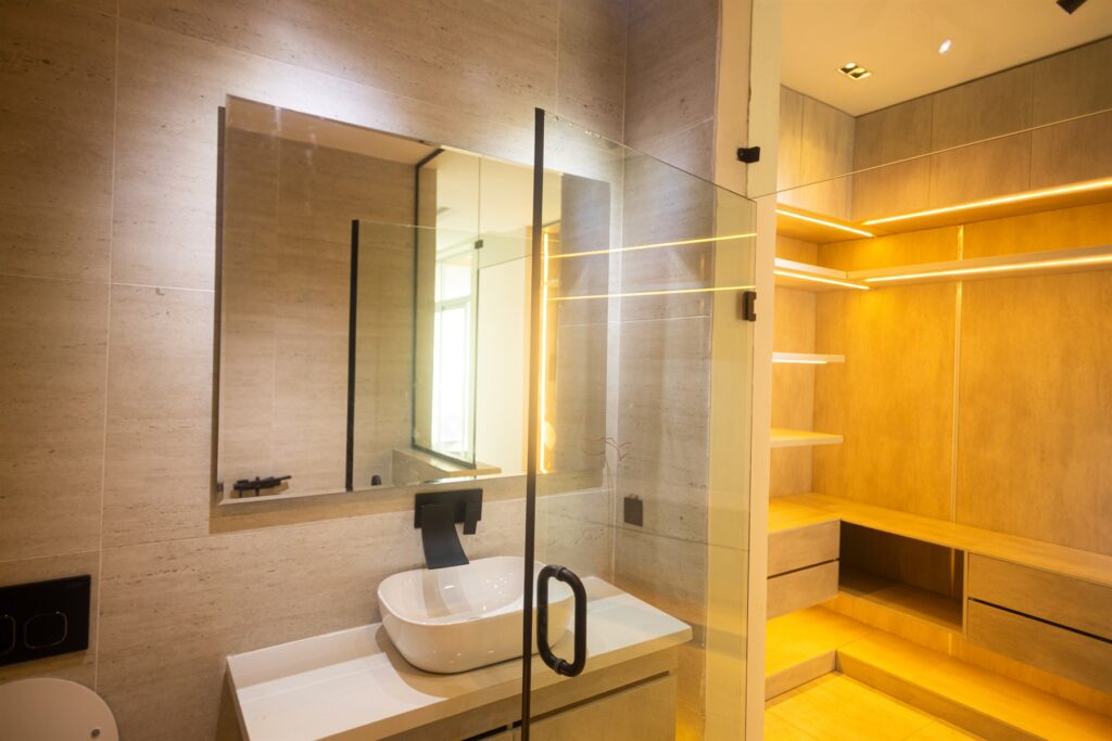 Brum Height 6: Bathroom basin and mirror beside a dressing area